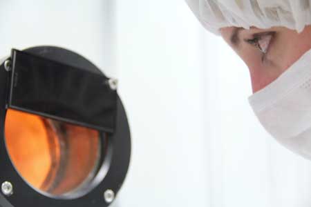 Woman looking into optical coating machine